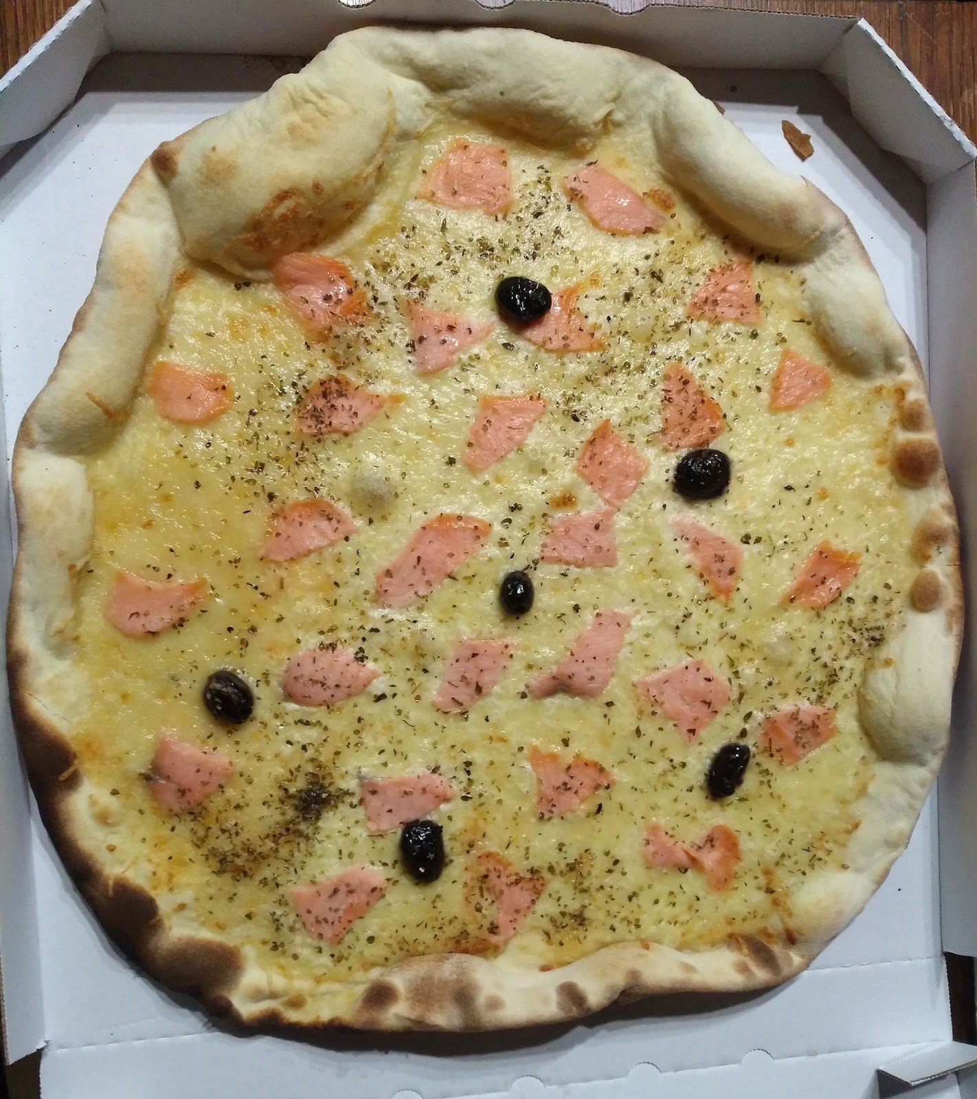 Pizza blanche au saumon et aux olives noires dans sa boîte