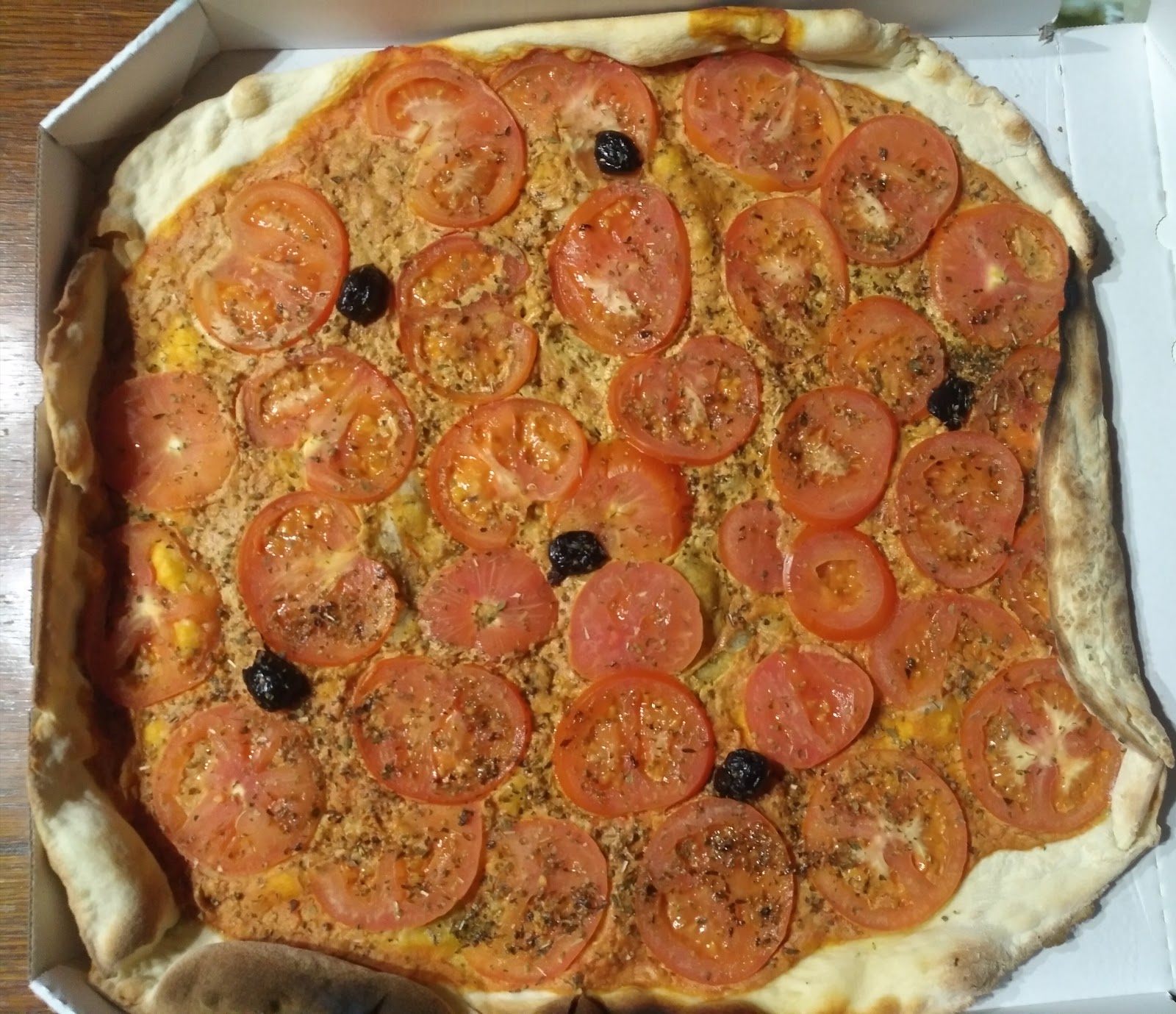 Pizza couverte de rondelles de tomates fraîches et d'origan