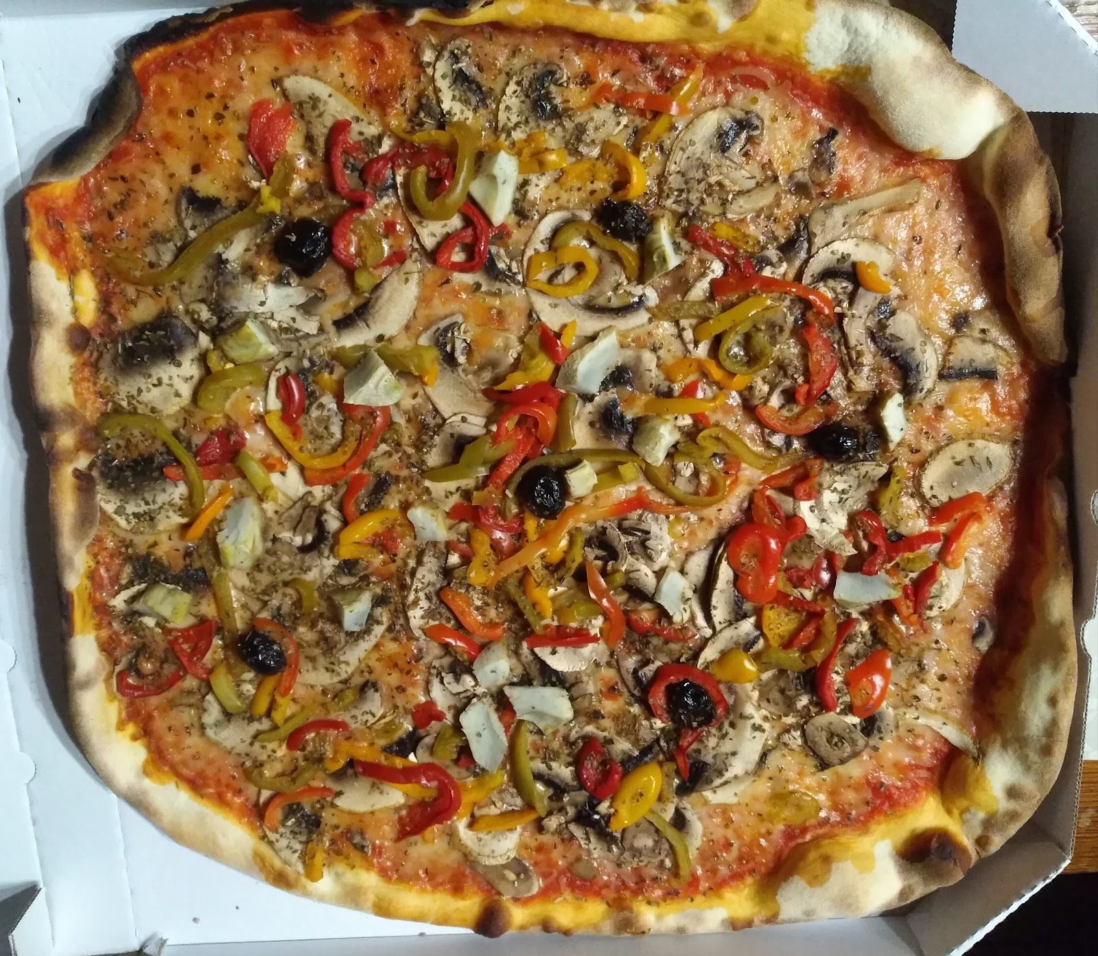 Pizza végétarienne généreusement garnie de champignons, poivrons et artichauts