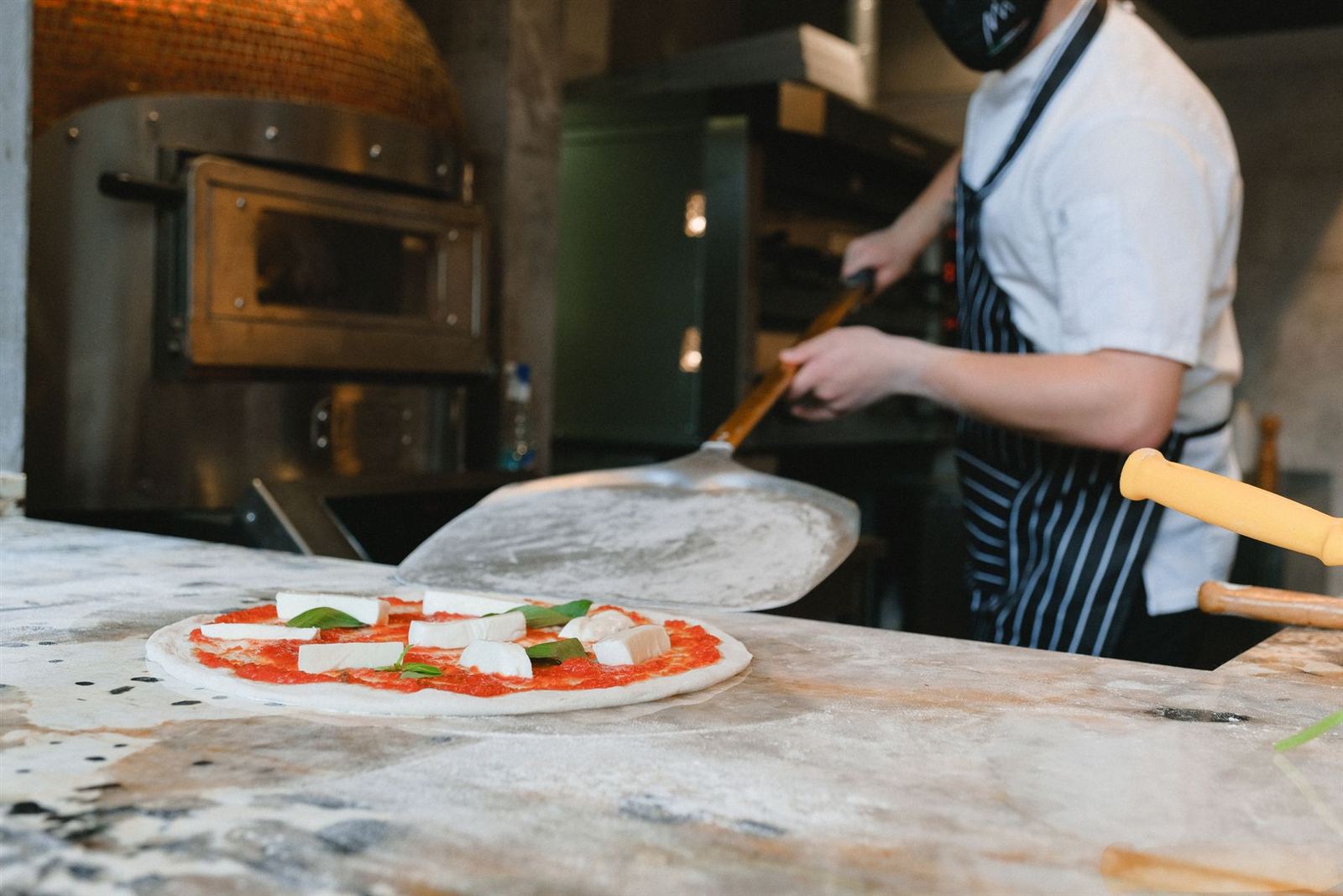 Un pizzaïolo enfourne une pizza (photo d'illustration)