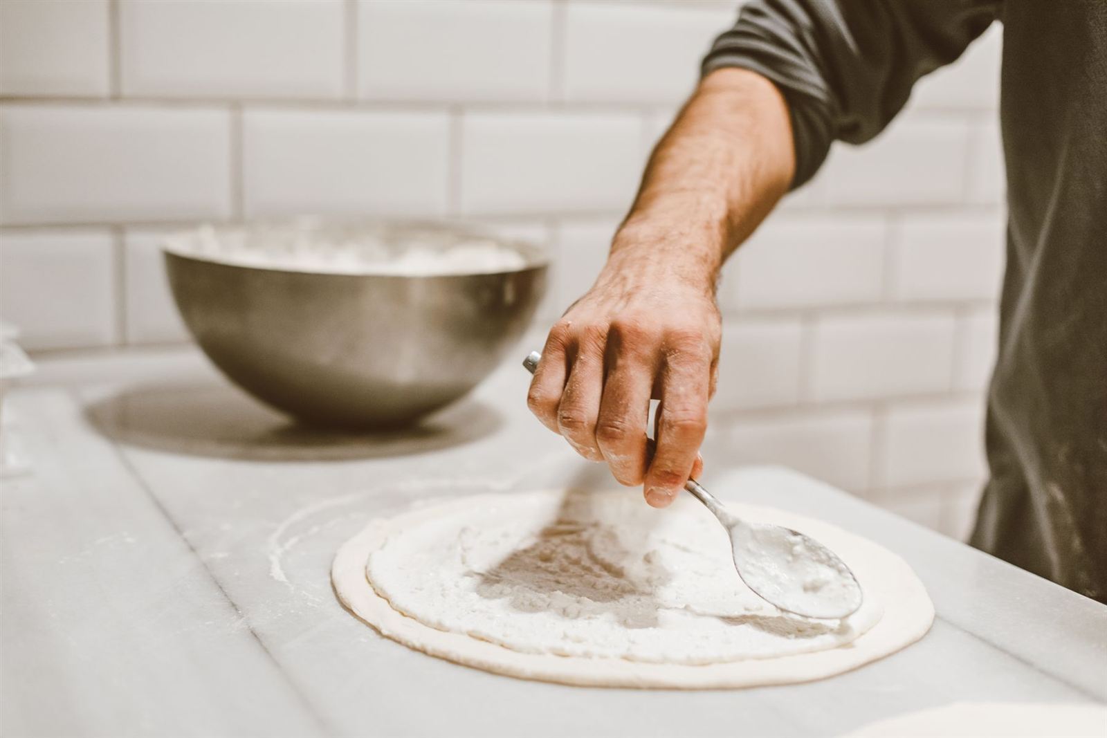 Étalement de la sauce sur une pâte à pizza (photo d'illustration)